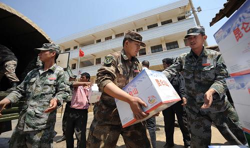 4月11日,在云南省尋甸回族彝族自治縣仁德鎮(zhèn)小多姑村,解放軍戰(zhàn)士幫助當(dāng)?shù)厝罕姲徇\(yùn)礦泉水。新華社記者 藺以光 攝
