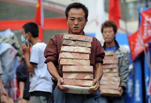 8月14日,志愿者在舟曲縣三中受災(zāi)群眾安置點(diǎn)搬運(yùn)磚塊。新華社記者 王鵬 攝