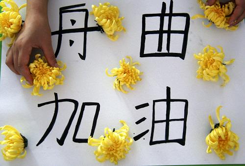 8月14日,山東郯城縣新愛嬰幼兒園的一名老師為舟曲遇難同胞獻(xiàn)上黃菊,寄托哀思。新華社發(fā)(張春雷 攝)
