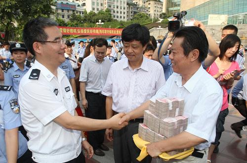 8月14日,民合公司代表周先生從警方代表手中領(lǐng)回發(fā)還的85萬元現(xiàn)金。新華社記者 陳誠(chéng) 攝