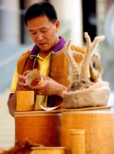 8月19日,一位鄂倫春族年輕人在展示鄂倫春族傳統(tǒng)的樺皮、獸皮工藝品。新華社記者 任軍川 攝