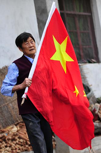 9月29日早晨,三峽移民顏道英在自家門前準備升國旗。新華社發(fā)(鄭家裕 攝)