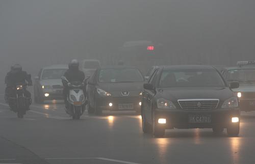 2月22日晨,江蘇揚(yáng)州市街頭,汽車(chē)亮著燈在濃霧里緩慢行駛。新華社發(fā)(莊文斌 攝)