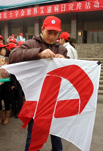 12月1日,在鄭州市的河南人民會(huì)堂廣場(chǎng)上,一名大學(xué)生在組裝一只“紅絲帶”風(fēng)箏。