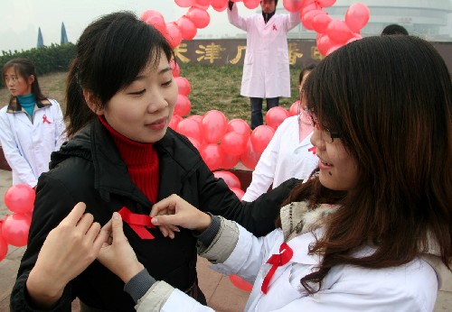 12月1日,在天津天塔公園參加“青春紅絲帶”行動(dòng)的志愿者為女青年佩戴紅絲帶。