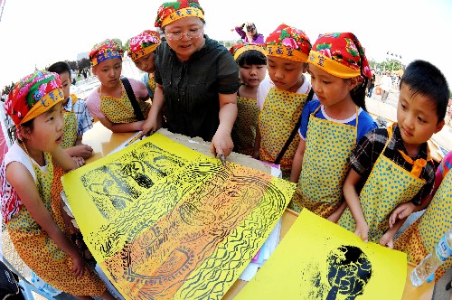 6月13日,在連云港舉行的大型非物質(zhì)文化遺產(chǎn)展演活動(dòng)中,小朋友們向老師展示版畫作品。 當(dāng)日是我國第四個(gè)“文化遺產(chǎn)日”,江蘇連云港市在蒼梧綠園舉辦非物質(zhì)文化遺產(chǎn)大型展演活動(dòng),當(dāng)?shù)貍鹘y(tǒng)手工藝、傳統(tǒng)戲曲等悉數(shù)亮相。 新華社發(fā)(王春 攝)
