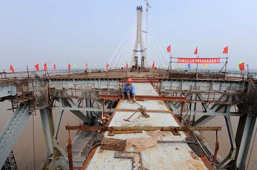 9月10日,大橋主橋最后一處鋼梁成功拼裝完成。 9月10日,在我國鐵路建設(shè)史上具有里程碑意義的武漢第6座長江大橋——天興洲長江大橋順利實(shí)現(xiàn)江中合龍,計劃于明年上半年建成通車,建成后將創(chuàng)下4項(xiàng)世界之最。 據(jù)介紹,總投資約110億元的天興洲大橋,正橋全長4657米,是目前世界上跨度最大的公鐵兩用斜拉橋。其主跨達(dá)504米,超過了當(dāng)今世界公鐵兩用斜拉橋中跨度第一的丹麥海峽大橋490米的跨度。 新華社記者程敏攝