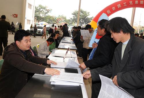 1月16日,工作人員(左)給農(nóng)民工群眾發(fā)放有關(guān)勞動(dòng)法的宣傳資料。新華社記者 藺以光 攝
