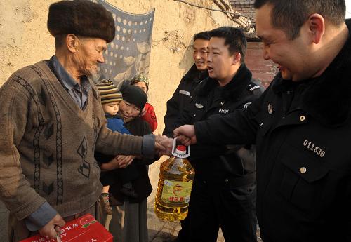1月20日,烏魯木齊市公安局特警支隊四大隊的特警隊員為烏魯木齊延安路街道辦事處延安新村社區(qū)的木沙·尼亞孜(左一)送來水果和糧油。新華社發(fā)