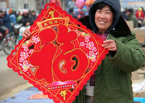 2月6日,一名農(nóng)村婦女在山東省郯城縣郯城鎮(zhèn)歸義西村年集上購(gòu)買春節(jié)飾品。新華社發(fā)(張春雷 攝)