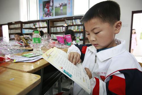 6月29日,在在四川省眉山市洪雅縣,符場中心小學(xué)的學(xué)生在圖書室內(nèi)閱讀“彩虹家園”提供的課外圖書。當(dāng)日,以關(guān)愛留守兒童為主旨的“彩虹家園”工程今年首個新增教育基地在四川省眉山市洪雅縣符場中心小學(xué)揭牌。該小學(xué)擁有留守兒童212名,他們將利用“彩虹家園”提供的視頻設(shè)施,增進(jìn)與外出打工父母之間的聯(lián)系。“彩虹家園”工程由聯(lián)合利華公司攜手全國婦聯(lián)開展,通過在各地興建教育基地,并利用視頻連線等方式,聯(lián)動鄉(xiāng)村留守兒童與城市務(wù)工的父母,促進(jìn)留守兒童的健康成長。新華社記者 任正來 攝
