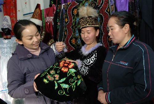 12月6日,哈薩克族刺繡高手加娜爾古麗(中)向顧客展示民族刺繡產(chǎn)品。