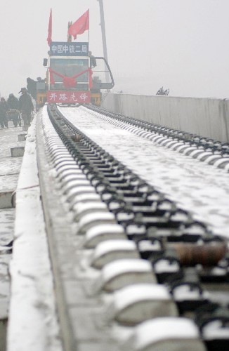 12月10日,中鐵二局的施工人員在風雪中鋪軌。