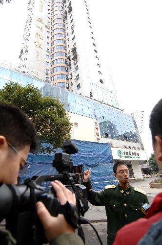 12月13日,一名警官在溫富大廈樓下向新聞媒體介紹滅火情況。