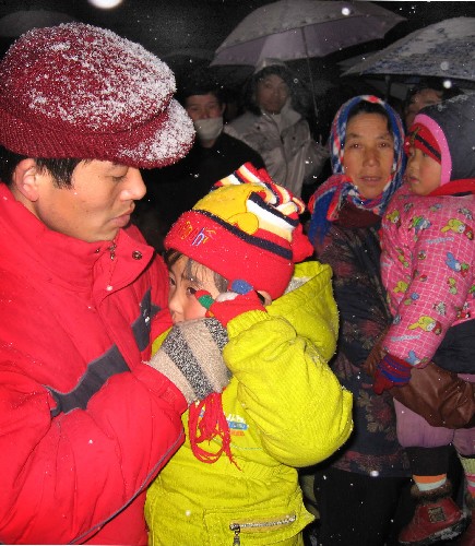 1月27日深夜,在合肥火車站廣場(chǎng),一名小朋友(左二)在給外地的親人打電話。
