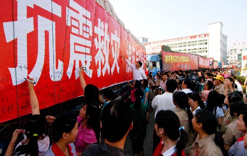 5月17日下午,浙江浪莎集團(tuán)員工在愛心車隊(duì)的橫幅上簽名,祝愿災(zāi)區(qū)人民早日重建家園。 當(dāng)日,由5輛滿載帳篷、內(nèi)衣、襪子、餅干、方便面等生活物資的車輛組成的愛心車隊(duì),從浙江義烏出發(fā)直奔四川地震災(zāi)區(qū)。 新華社發(fā)(張建成 攝)