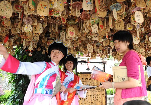 6月14日,納西族姑娘夏青(左)給游客發(fā)放保護(hù)麗江世界文化遺產(chǎn)的資料。