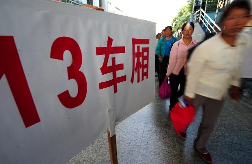 8月25日,在蘭州火車站,乘坐“棉農(nóng)專列”赴新疆摘棉的棉農(nóng)從車站引導(dǎo)牌旁走過。