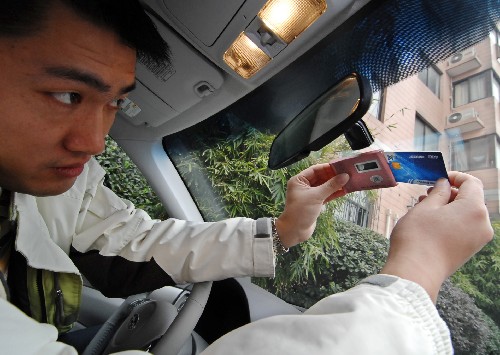 12月20日,一名駕駛員將插有專用結(jié)算卡的車載單元裝在汽車擋風(fēng)玻璃上。新華社發(fā)