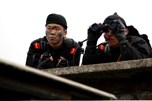 12月25日,參加演習的兩名特警隊員在制高點上對“歹徒”藏身的小樓進行偵察。新華社發(fā)(雷攀全 攝)