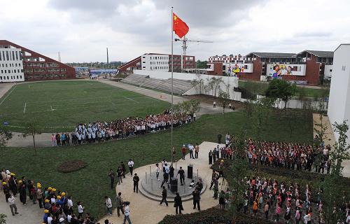 5月9日,綿竹市孝德鎮(zhèn)中小學(xué)生與建設(shè)工人在新落成的孝德中學(xué)舉行升旗儀式。 當(dāng)日,由江蘇省蘇州市援建的項目——孝德中、小學(xué)在四川省綿竹市交付使用,孩子們高興地從板房校舍搬入嶄新的學(xué)校,開始新的學(xué)習(xí)生活。新華社記者 楊磊 攝