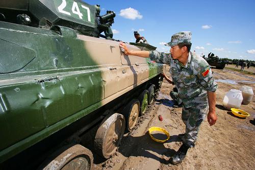 7月22日,參加演習的中方裝甲兵在認真擦拭戰(zhàn)車。新華社記者 查春明攝