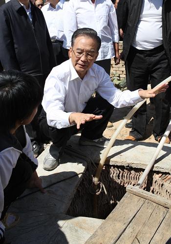 這是8月28日溫家寶來到赤峰市敖漢旗雙廟村一個(gè)農(nóng)戶家,察看院子里干枯的水井,詢問村民人畜飲水等情況。新華社記者劉衛(wèi)兵攝