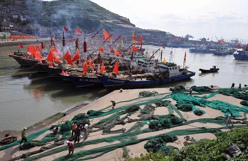 9月13日,浙江舟山市嵊泗縣黃龍鄉(xiāng)南港碼頭泊滿了漁船,漁嫂們在岸邊織補漁網(wǎng)。新華社發(fā)(吳琳紅 攝)