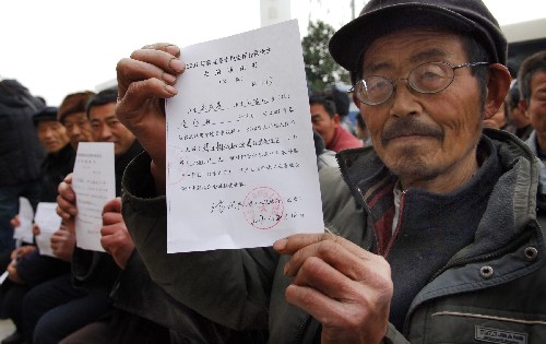12月5日,安徽省阜南縣王家壩鎮(zhèn)李郢村村民鄭應(yīng)普在展示補(bǔ)償款發(fā)放通知書(shū)。 新華社記者 李健 攝