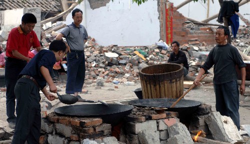 5月15日下午,在四川綿陽市平武縣南壩鎮(zhèn),幾位災(zāi)民在用大鍋煮飯。 南壩鎮(zhèn)由于道路中斷,一度與外界隔絕,目前成都軍區(qū)四川預(yù)備役高炮師向該地區(qū)運送了大量糧食、飲水、藥品,災(zāi)民生活得到基本保障。 新華社記者 江毅 攝