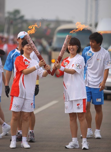 6月5日,火炬手劉娜(右二)與下一棒火炬手陳曉春交接后將兩支火炬擺成英文字母“V”字形狀。當(dāng)日,北京奧運(yùn)圣火在湖南湘潭傳遞。 新華社記者 邢廣利 攝