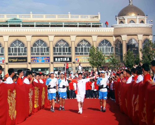 6月18日,火炬手阿迪力·吾守爾(中)手持火炬?zhèn)鬟f。當(dāng)日,北京奧運(yùn)圣火在新疆喀什傳遞?!⌒氯A社記者 邢廣利 攝