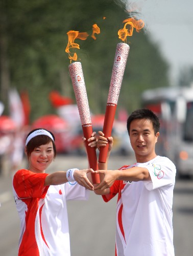 6月30日,火炬手郝偉(右)與下一棒火炬手王彬宸交接。當日,北京奧運圣火在寧夏吳忠傳遞。 新華社記者 邢廣利 攝