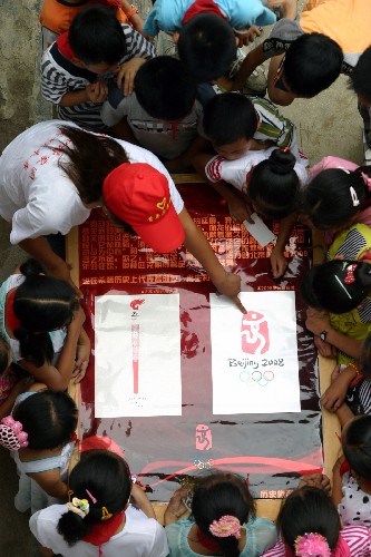 7月4日,一名大學(xué)生志愿者給留守小學(xué)生講解奧運(yùn)相關(guān)知識(shí)。 新華社發(fā)