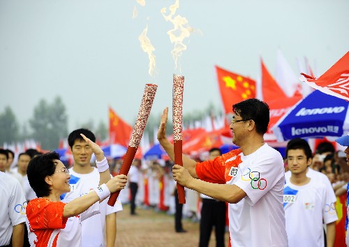 7月17日,火炬手孫永言(右)與下一棒火炬手王玲進行交接。當日,北京奧運圣火在沈陽市傳遞。 新華社記者 任勇 攝