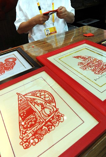 在青島奧運(yùn)村中國民俗展的展區(qū)內(nèi),藝人在現(xiàn)場制作剪紙作品(7月27日攝)。 新華社記者 王頌 攝