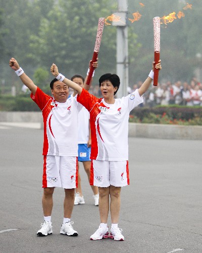 7月28日,火炬手李建安(右)與下一棒火炬手楊文周交接后合影。當(dāng)日,北京奧運圣火在河南省安陽市傳遞。 新華社記者 邢廣利 攝