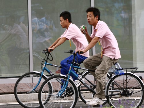 7月29日,在北京奧林匹克體育中心區(qū),兩名工作人員以自行車代步。 新華社記者 任瓏 攝