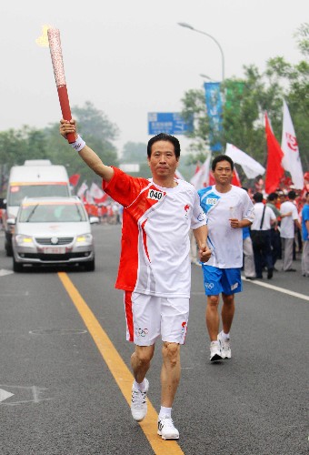 8月6日,火炬手、北京奧運會國家攝影隊領隊、新華社攝影部主任徐祖根手持火炬?zhèn)鬟f。當日,北京奧運圣火在北京市傳遞。 新華社記者 邢廣利 攝
