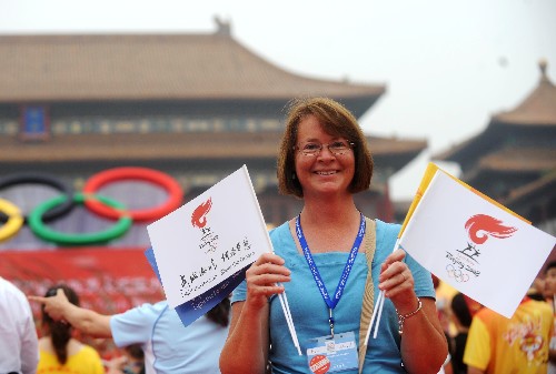 8月6日,一名來自美國加利福尼亞州的游客在北京故宮午門前手舉小旗為北京奧運加油。當日,北京奧運圣火在北京市傳遞。 新華社記者 羅曉光 攝