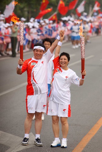 8月8日,火炬手李桂華(右)與下一棒火炬手劉長(zhǎng)銘交接后握手致意。當(dāng)日,北京奧運(yùn)圣火在北京市傳遞。 新華社記者 邢廣利 攝