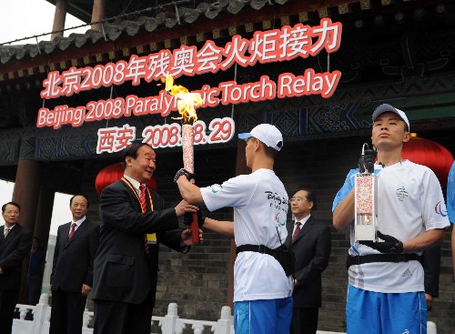 8月29日,北京奧組委執(zhí)行副主席蔣效愚(前左)接過火炬。當(dāng)日,北京殘奧會圣火在西安進(jìn)行傳遞。 新華社記者 金良快 攝