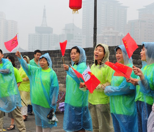8月29日,西安市民冒雨為火炬手加油。當(dāng)日,北京殘奧會圣火在西安進(jìn)行傳遞。 新華社記者 張善臣 攝