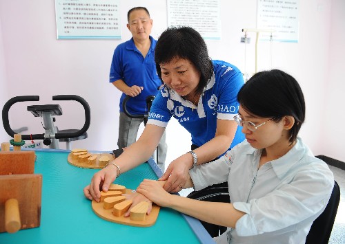 9月3日,志愿者在北京朝陽區(qū)安貞街道溫馨家園幫助偏癱患者鄭瑜(右一)使用手指分離板。當日,包括紅十字、殘聯、郵政、地鐵、公交等多個部門的百萬殘奧會社會志愿者在社會公共場所開展了秩序維護、文明倡導、環(huán)境美化和扶危助困等各類志愿服務活動,掀起了迎接殘奧會扶殘助殘活動的高潮,為即將到來的殘奧會志愿服務工作打下良好基礎。 新華社記者 羅曉光 攝