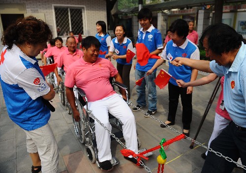 9月3日,志愿者在北京朝陽區(qū)安貞街道溫馨家園為做輪椅拔河游戲的殘疾人朋友加油助威。 新華社記者 羅曉光 攝