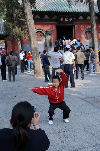 10月19日,在河南嵩山少林寺門(mén)前,一位小朋友在留影。 記者在河南一些著名旅游景點(diǎn)看到,雖然黃金周已過(guò),但這些景點(diǎn)依然游人如織。據(jù)了解,很多游客專門(mén)避開(kāi)黃金周利用休息日游玩。 新華社記者劉海峰攝