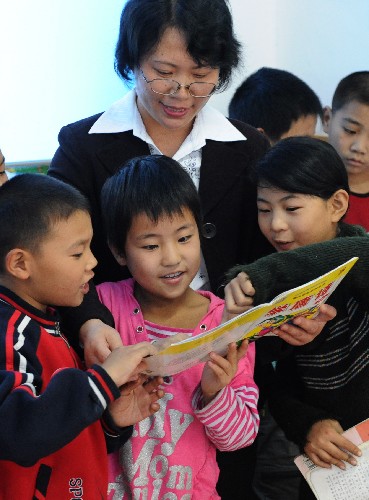 10月19日,課外輔導(dǎo)員在和孩子們一起閱讀書籍。 河南省漯河市三里橋小學(xué)于2008年9月創(chuàng)辦了留守兒童之家,孩子們節(jié)假日可以在這里靜心閱讀、制作手工、快樂玩耍,使他們在幸福的體驗(yàn)中學(xué)會(huì)感恩,學(xué)會(huì)助人,這里成了留守兒童們的幸福家園。 新華社記者丁海濤攝