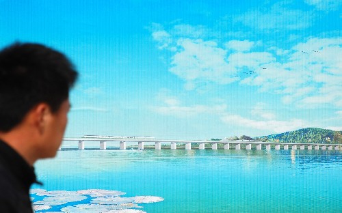 4月26日,一位市民觀看正在施工的京滬高鐵丹昆特大橋陽澄湖橋段效果圖。 新華社發(fā)