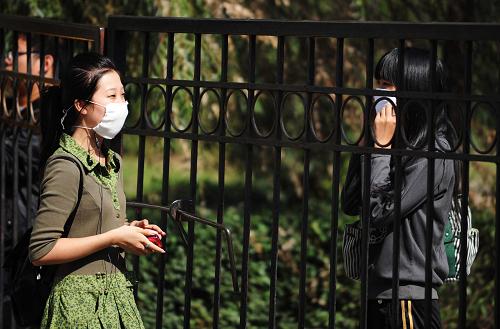 9月16日,兩名戴口罩的女生隔著鐵門交流。新華社記者 王建威 攝
