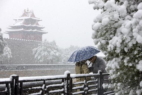 11月1日,在北京故宮角樓附近,一對夫婦在觀看剛剛拍攝的雪景照片。當日,受寒潮影響,一場瑞雪降落京城。記者從北京市氣象臺了解到,目前,北京正處于由深秋向初冬過渡時期,這次強勁的寒潮讓北京今冬初雪比去年提前了2個月,但寒潮過后,氣溫將開始回升至正常值數(shù)。此外,京城的這場“深秋”降雪之所以越來越大,除了寒潮影響外,也有人工干預的原因。新華社記者 沈伯韓攝